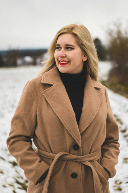 a woman in a brown coat standing outside