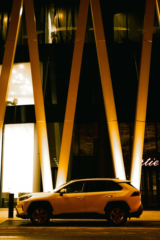 the car is parked beside the tall yellow building