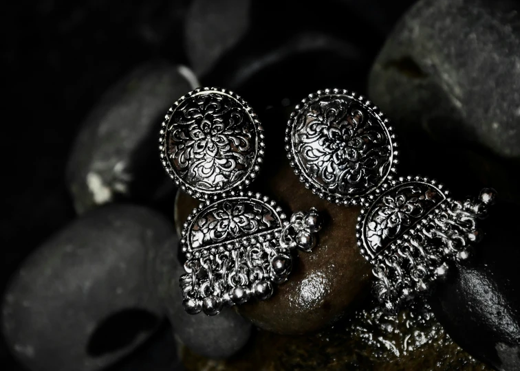 silver earrings sitting on top of rocks in the dark