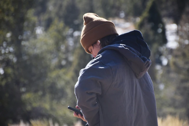 a boy wearing a hat looking at his cell phone