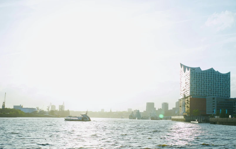 a boat moving in the ocean, with the tall buildings to the side