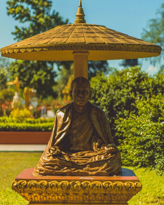 a golden buddha statue is sitting in a garden