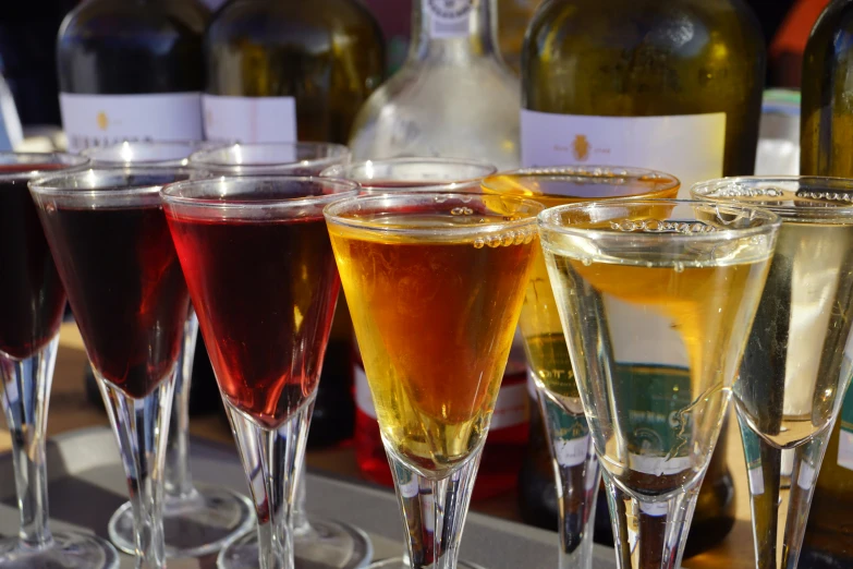 several glasses filled with different drinks sitting next to bottles