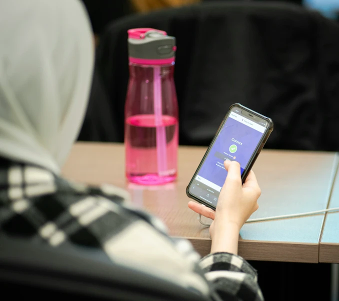 a person sitting down while holding their phone up to their screen