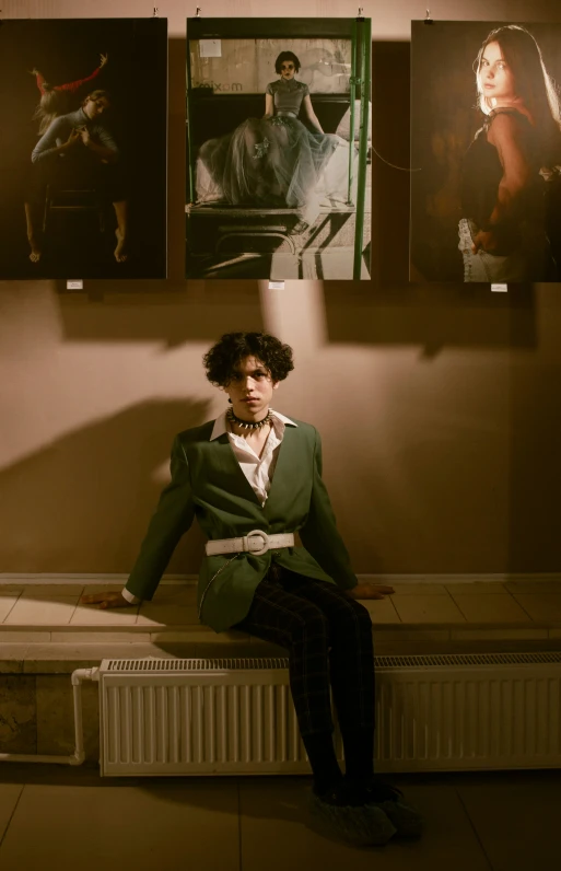 man sitting on a table with three paintings behind him