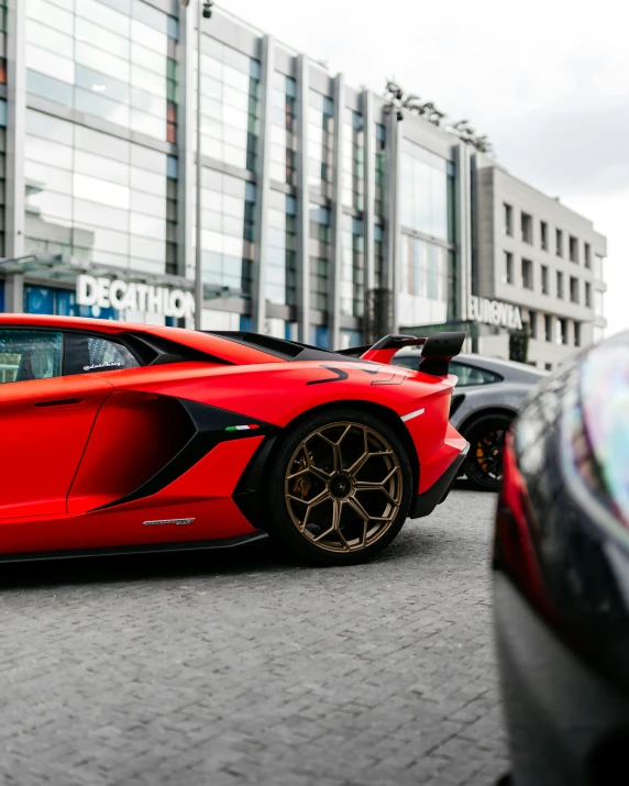 a red sports car is on the street and is facing away from some other vehicles