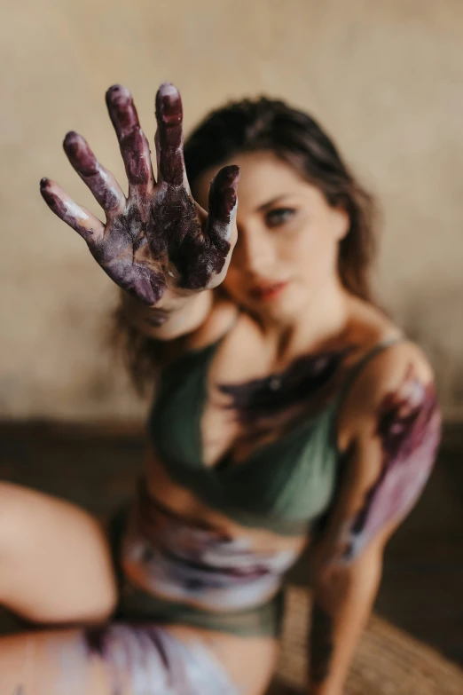 a young woman covered in body paint with her hand in the shape of a hand