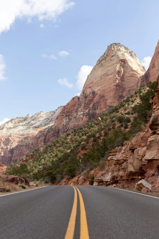 a car driving on a mountainous road near trees and mountains