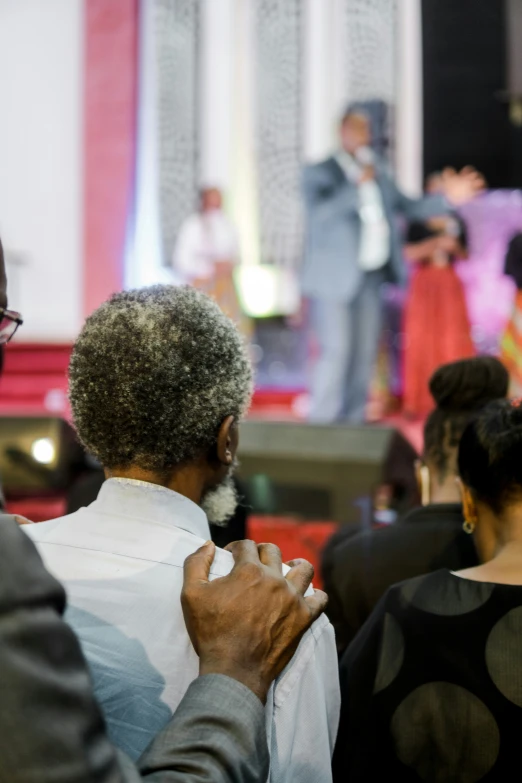 a man holds up a white bowtie to another mans chest