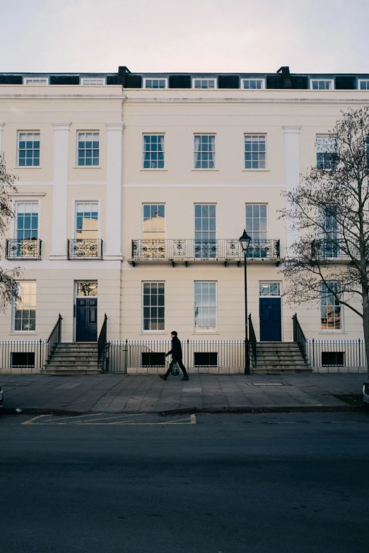 a person walks past two white buildings