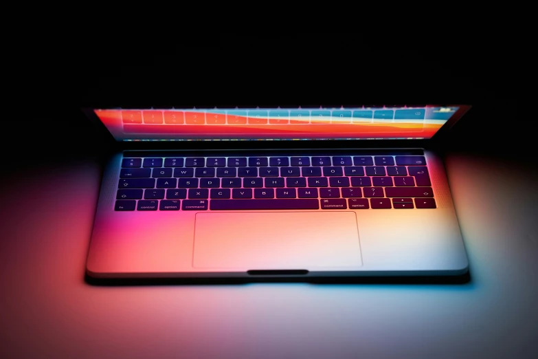 a laptop sitting on the table illuminated in color