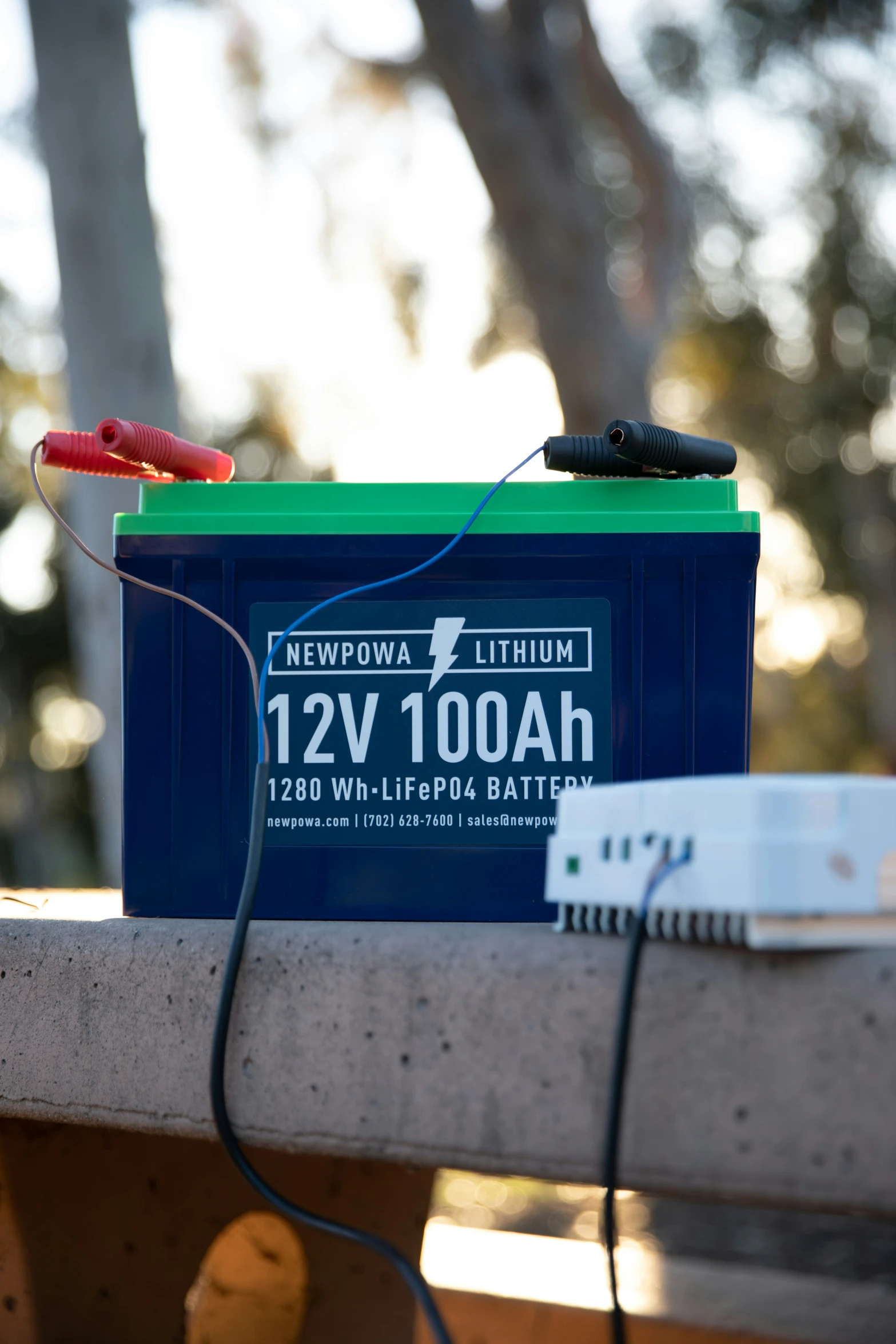 a battery attached to a power strip and wires on a wooden bench