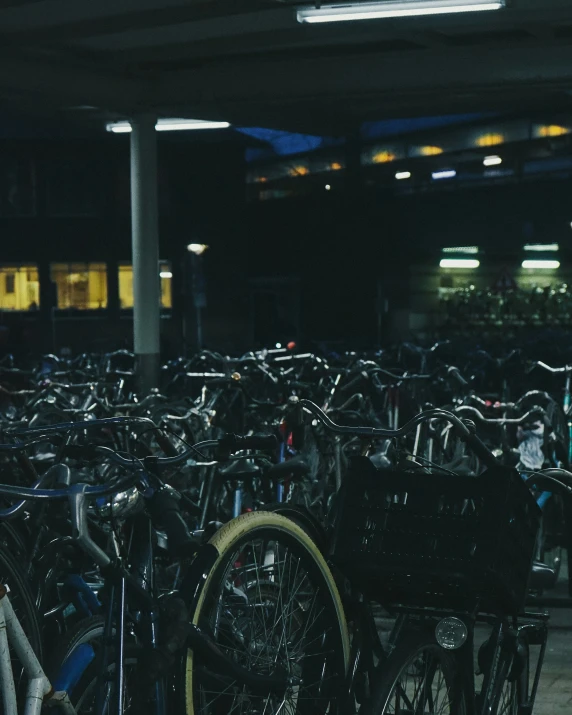 many bicycles parked in an indoor area at night