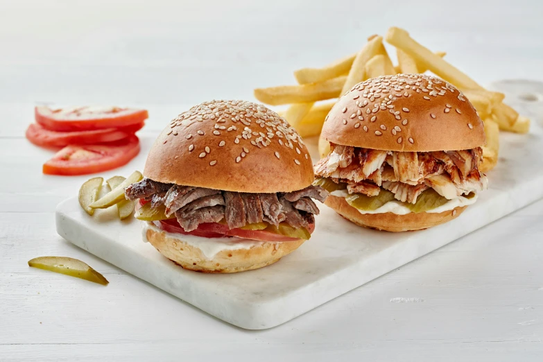 two beef sandwiches on a white platter with french fries