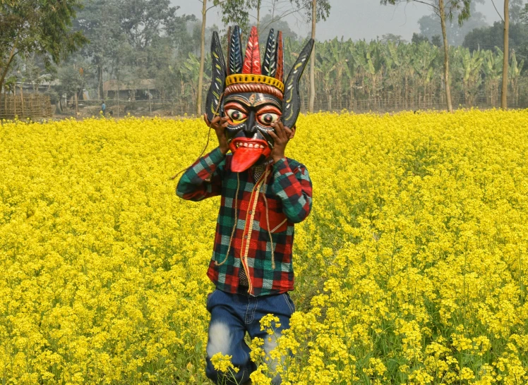 a man wearing a mask walking through a yellow field