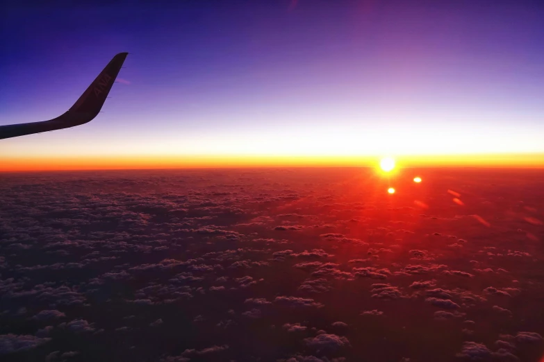 an airplane wing with a sun coming down over it