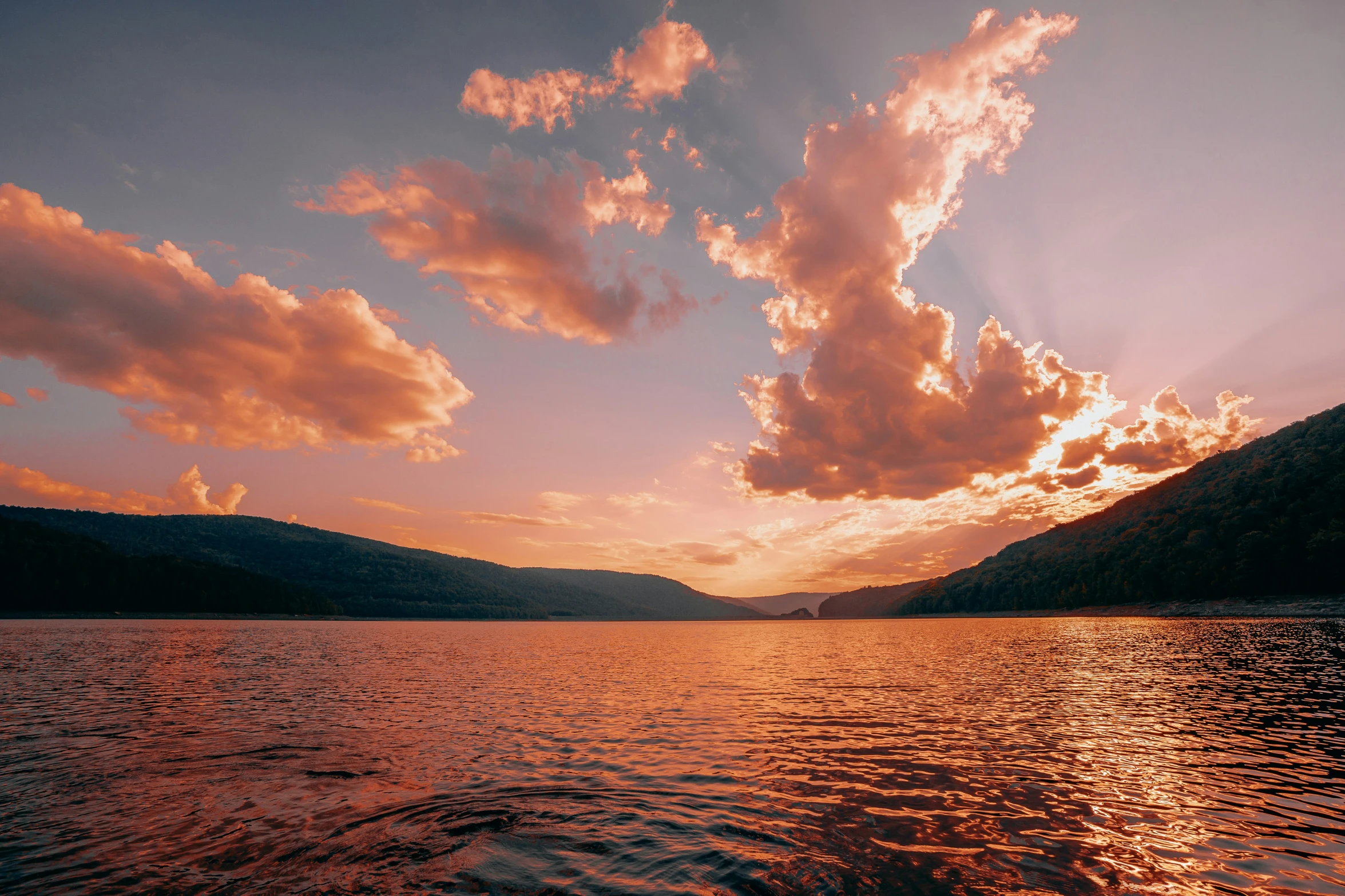 beautiful sunset with clouds over the mountains and water