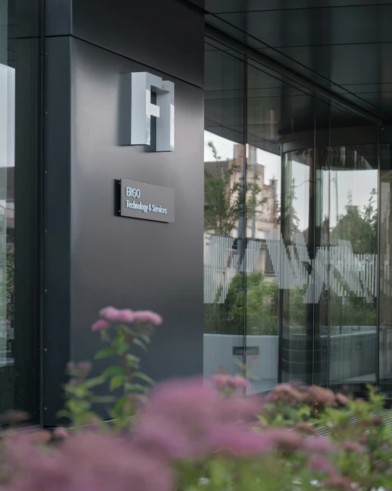 a very modern building with glass doors and flowers in front