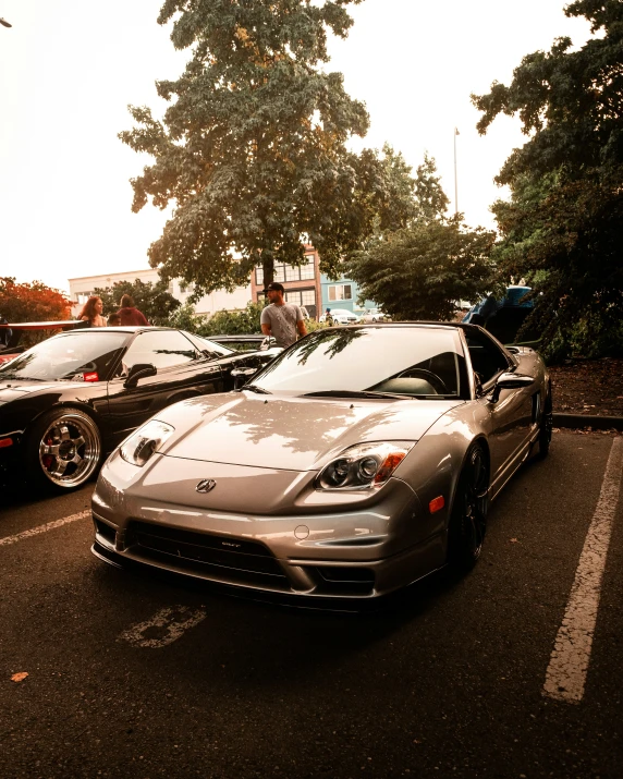 two sports cars in a parking space surrounded by trees