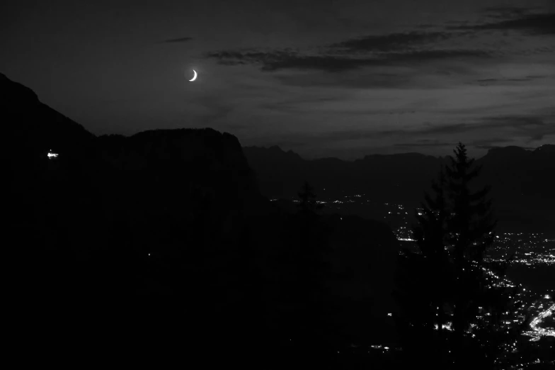 the night scene shows mountains and the moon in a cloudy sky