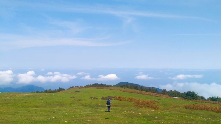 a person on a grassy hill with the mountains in the background