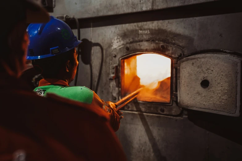 a worker using a hose to douse a hole in the wall