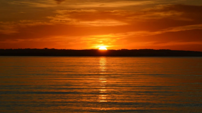 a sun is setting on the horizon over a body of water