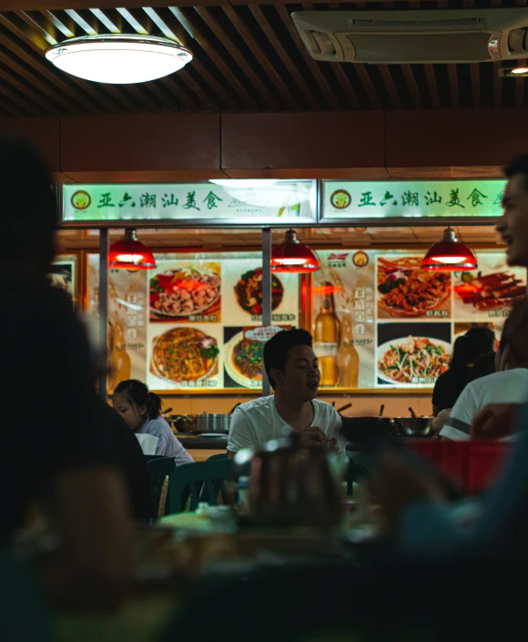 people are seated at a table near a pizza stand