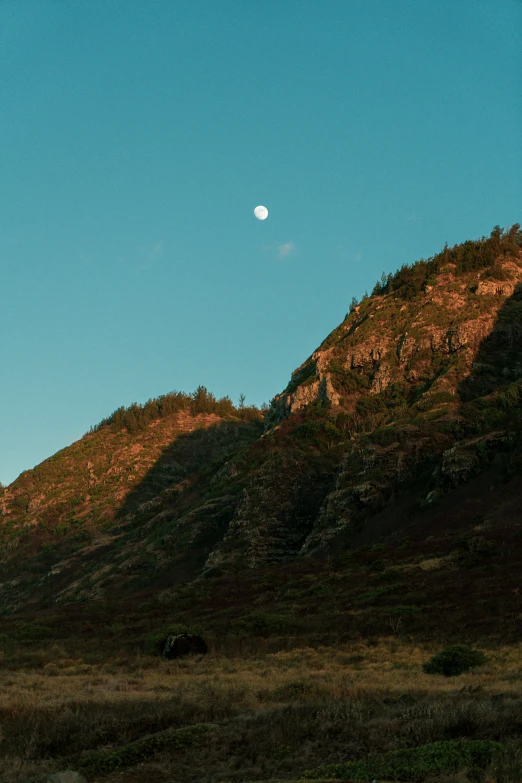 a moon is shining off the side of a hill