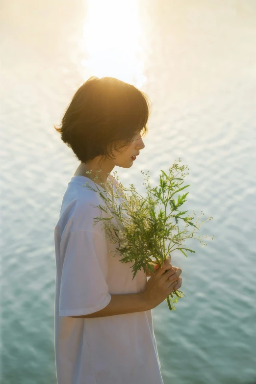 a girl holding some flowers by the water