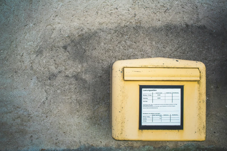 a yellow square type device is attached to a cement wall