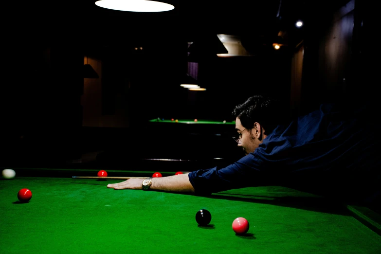 a man leaning over a pool table looking down at some balls