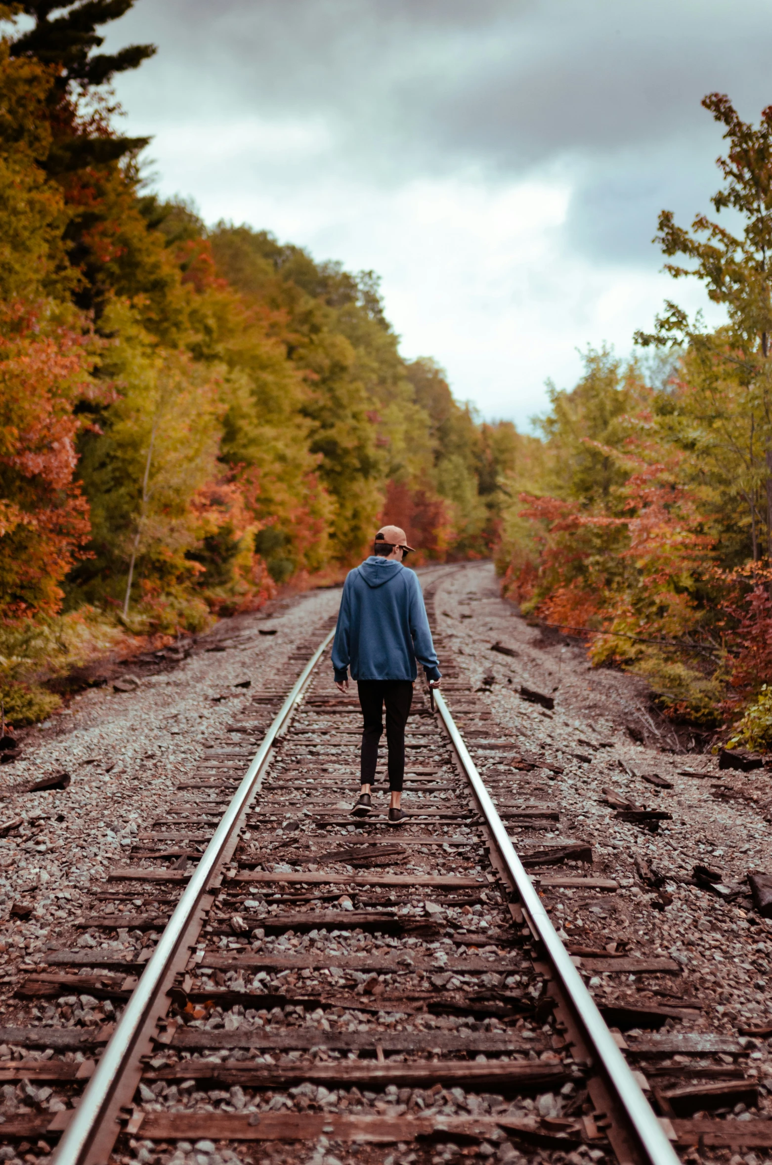 a person in blue walking down a railroad track