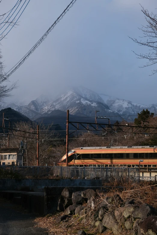 an orange train is in the mountains under wires