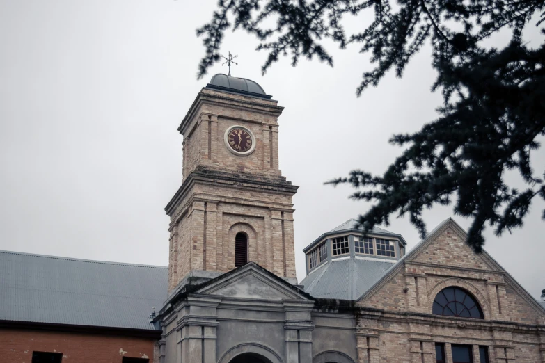 a clock tower rises over the building on a cloudy day