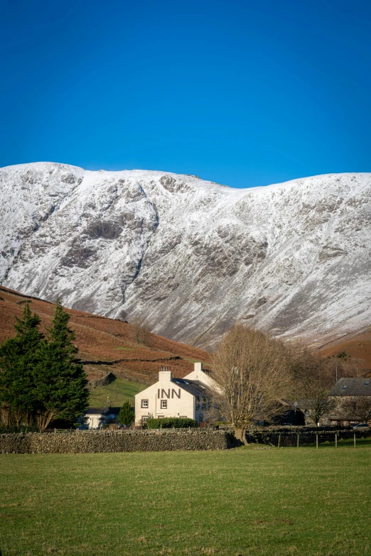 a house on the side of a road with snowy mountain behind it