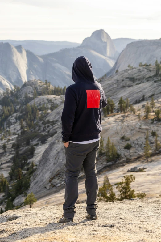 a man is standing on the mountain looking out at a valley