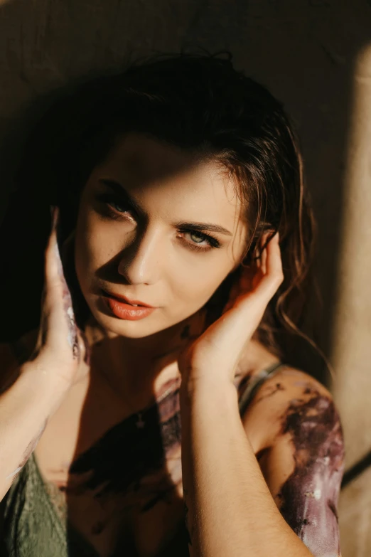 a woman standing in a room near a wall holding her hands near her face