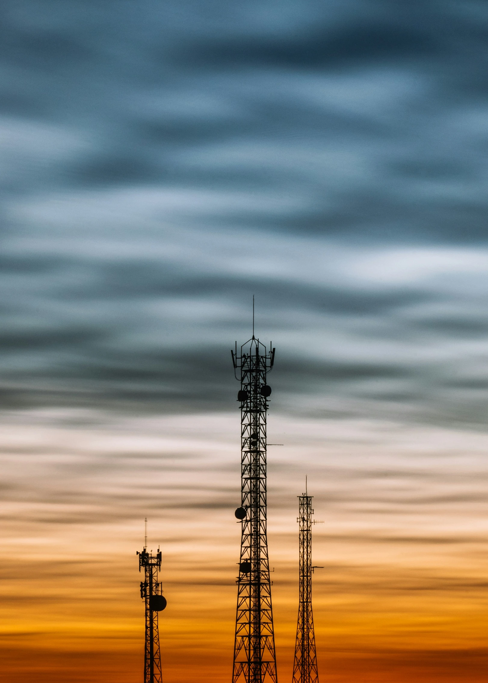 a couple of cellular towers sitting on top of a lush green field