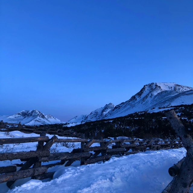 a mountain peak towering over a snow covered hillside