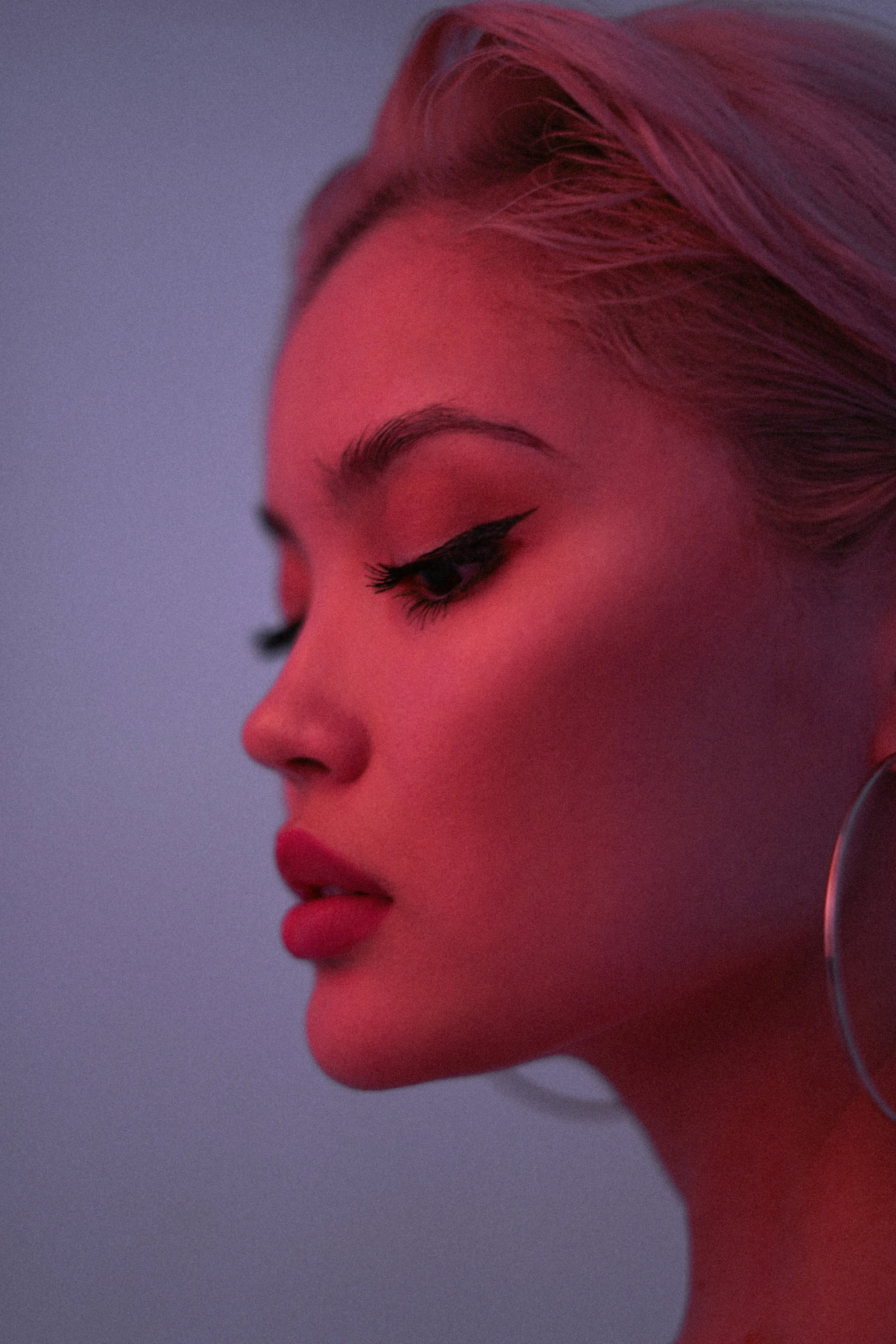 a woman's profile with her face lit up with a purple background