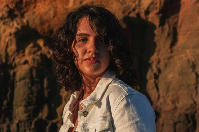 woman with curly hair and white shirt posing near rock formations