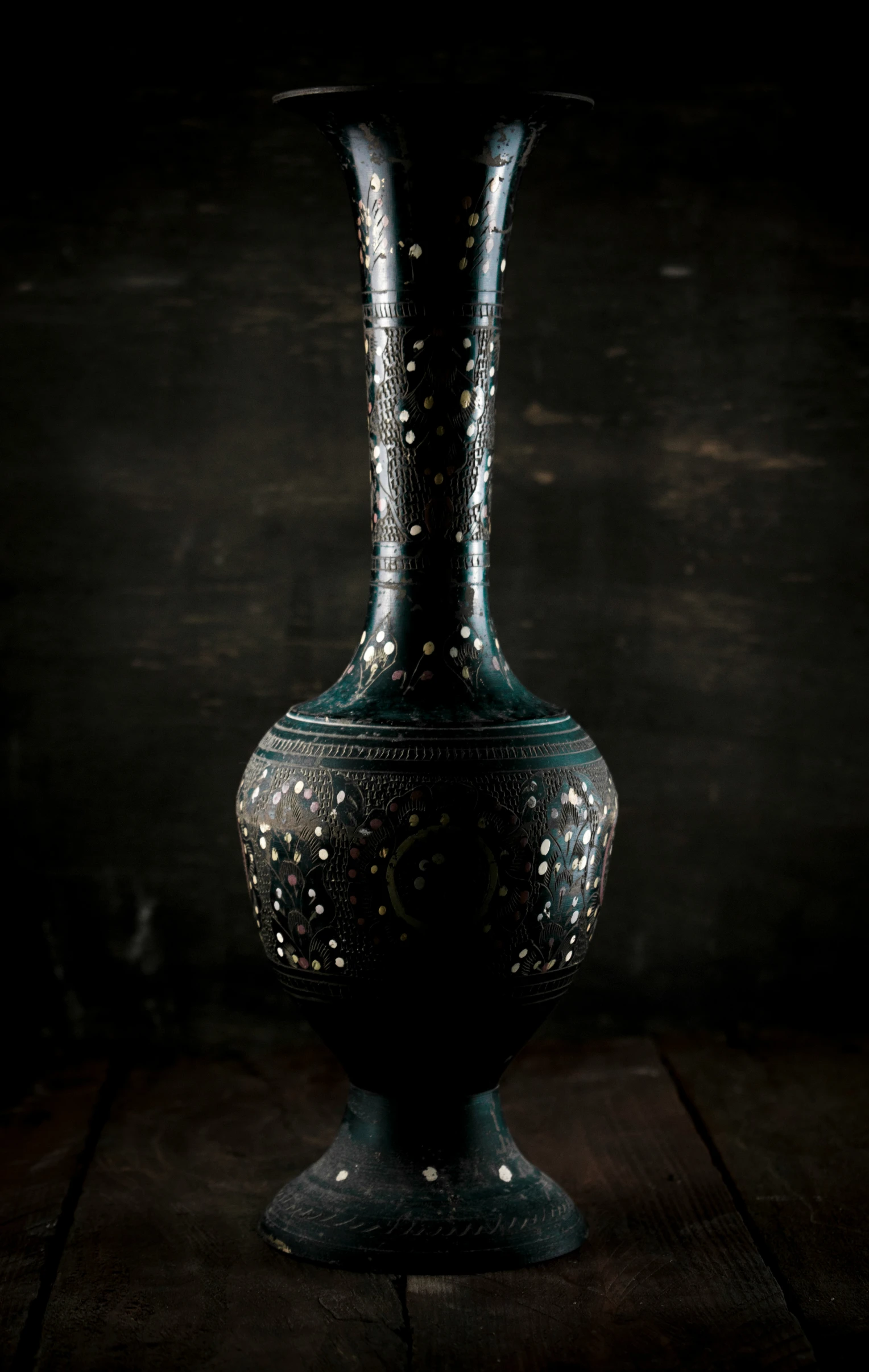 a black vase sits on a wooden table
