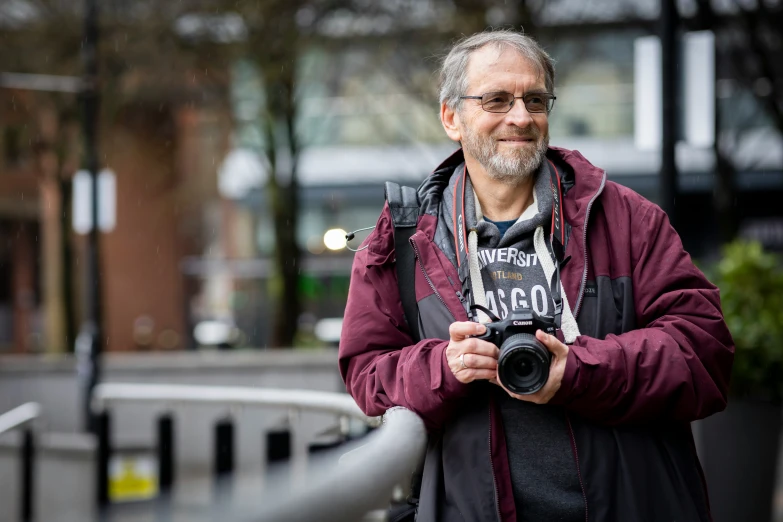 man holding a camera in a park, he is smiling