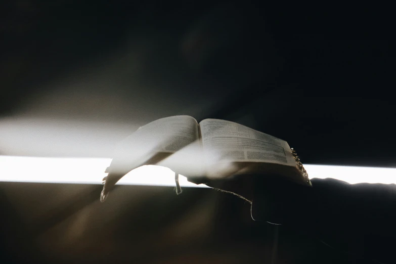 an open book being held in hand in a dark room