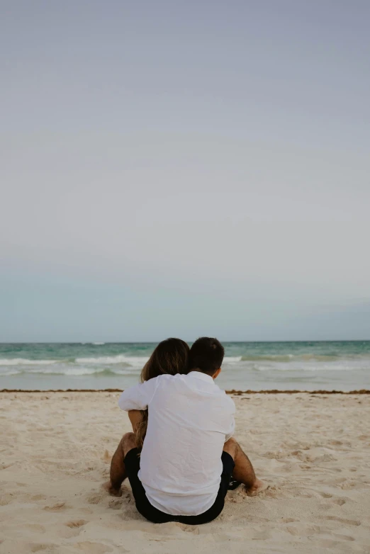 a couple sitting on top of a sandy beach
