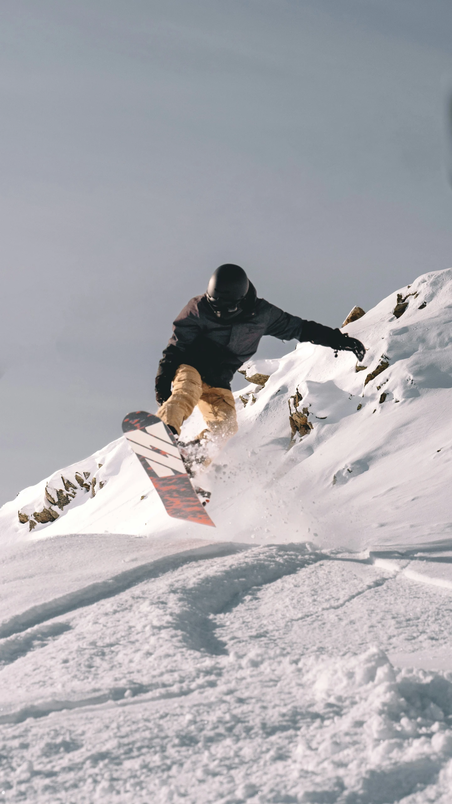 snowboarder on steep snowy hill with bright light coming from the clouds