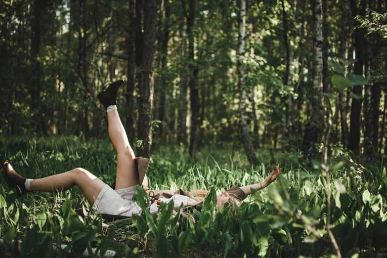 a person laying down in the grass on the forest