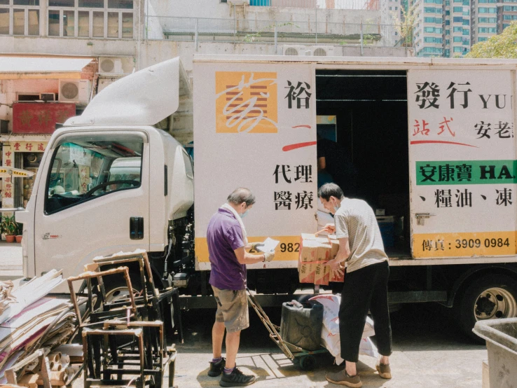 people stand next to a delivery truck and box of food