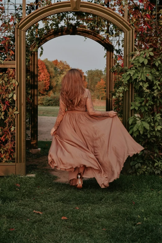 an attractive woman sitting on a grassy area under an arch